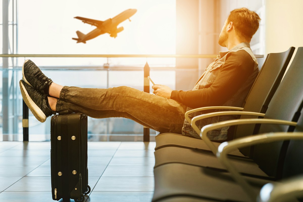 Traveller relaxing at the airport gate watching a plane take off