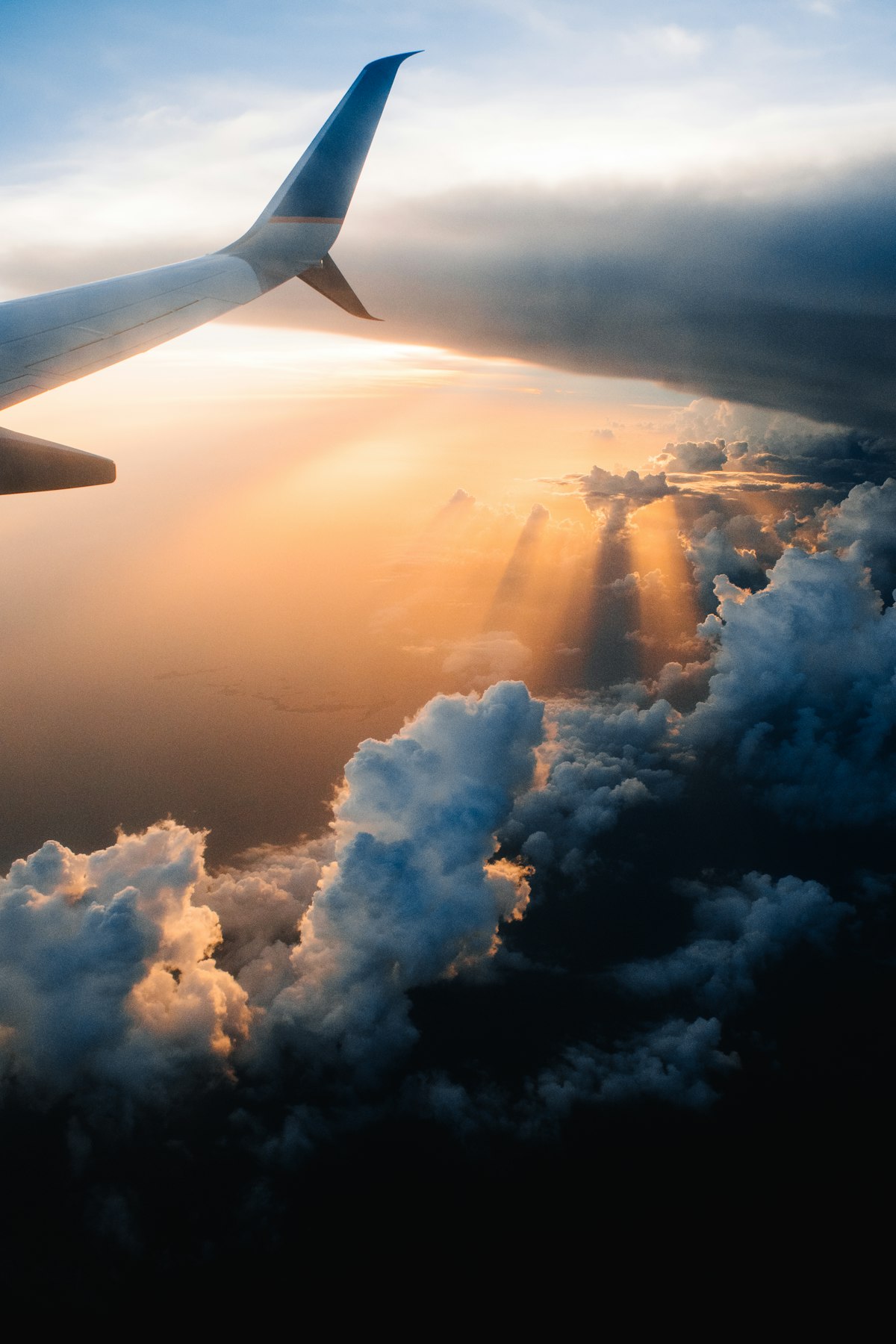 View of an aircraft wing above the clouds at sunset from a plane window